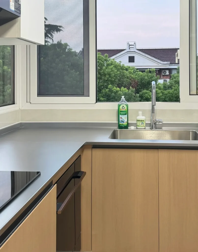 Close-up detail of the slim profile 2cm stainless steel countertop with integrated sink and faucet in a modern small kitchen design